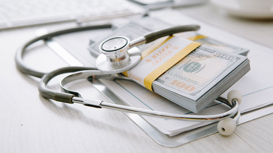 Stethoscope and a stack of money representing new 2022 legislation to protect patients from receiving surprise medical bills for emergency services.