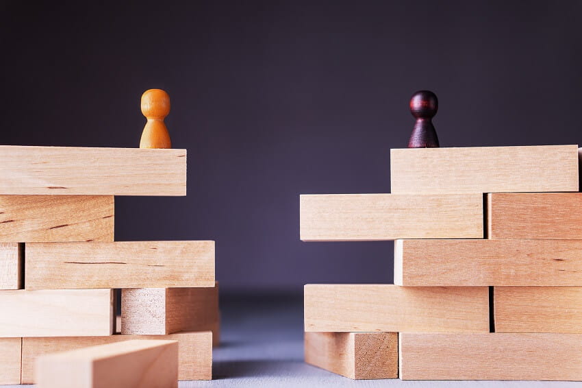 Two pawn chess pieces, each atop a different stack of blocks, representing business partners splitting up their assets and busines.