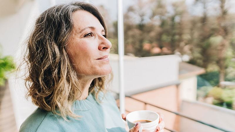 Una mujer con un café mirando a lo lejos