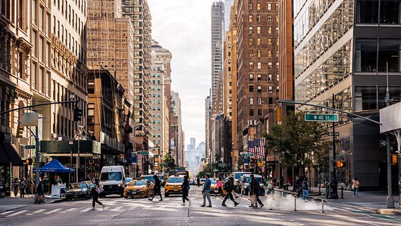 Personas cruzando una calle concurrida en un distrito céntrico de una gran ciudad